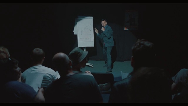 Video Reference: Entertainment, Chair, Performing arts, Event, T-shirt, Darkness, Fun, Suit, Conversation, Presentation