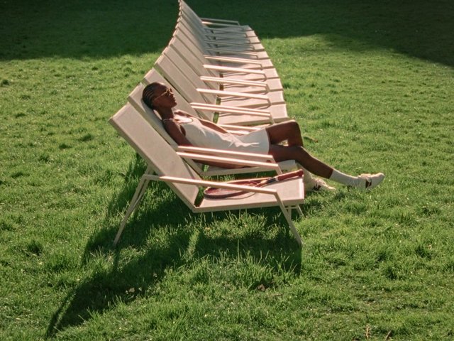 Video Reference: woman, lounging, lawn, grass, sunlight, outdoors, deck chairs, white dress, relaxation, summer, park, reclining, shadows, green, casual, leisure