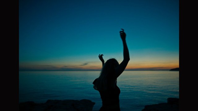 Video Reference: silhouette, person, sunset, sea, ocean, beach, sky, horizon, evening, arms raised, back view, travel, nature, waterscape, serene, coastline