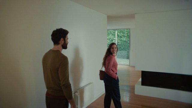 Video Reference: interior, modern home, empty room, couple, two people, indoor, wood floor, large window, natural light, smiling, real estate, house tour, living space, minimalist, residential
