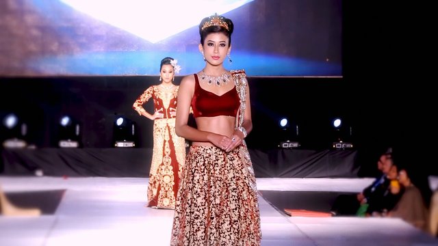 Video Reference: fashion show, runway, model, traditional dress, formal wear, jewelry, stage, catwalk, competition, event, lighting, audience