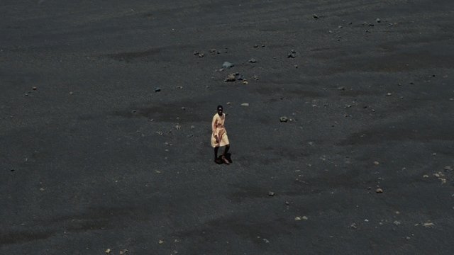Video Reference: person, alone, rocky ground, barren landscape, high angle, wide shot, outdoors, dark terrain, solitary, minimalism