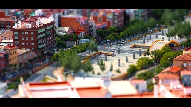 Video Reference: cityscape, urban, neighborhood, apartments, plaza, park, trees, street, elevated view, tilt shift, architecture, residential, walkway, steps, outdoor, aerial