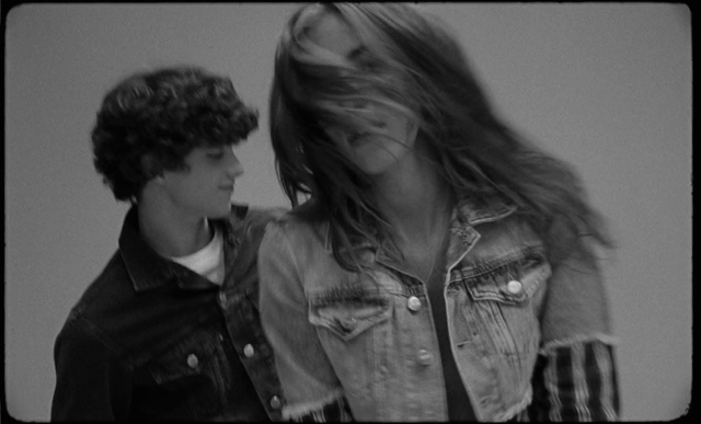 Video Reference: Hair, Outerwear, Flash photography, Sleeve, Happy, Gesture, Black-and-white, Grey, Style, Leather jacket