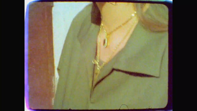 Video Reference: close-up, person, torso, jacket, shirt, necklace, vintage tv, low resolution, indoor, fashion, cropped, retro