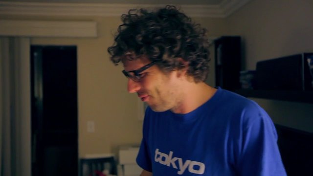 Video Reference: man, indoor, portrait, side profile, curly hair, glasses, blue shirt, room, casual, adult, standing, home interior