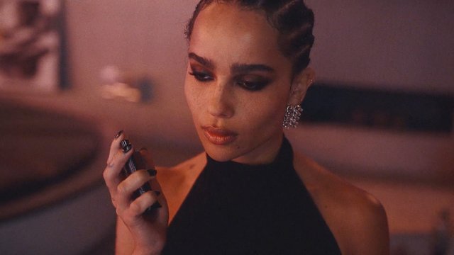 Video Reference: woman, close-up, braids, makeup, holding object, indoor, warm lighting, portrait, blurred background, fashion, elegant, dramatic
