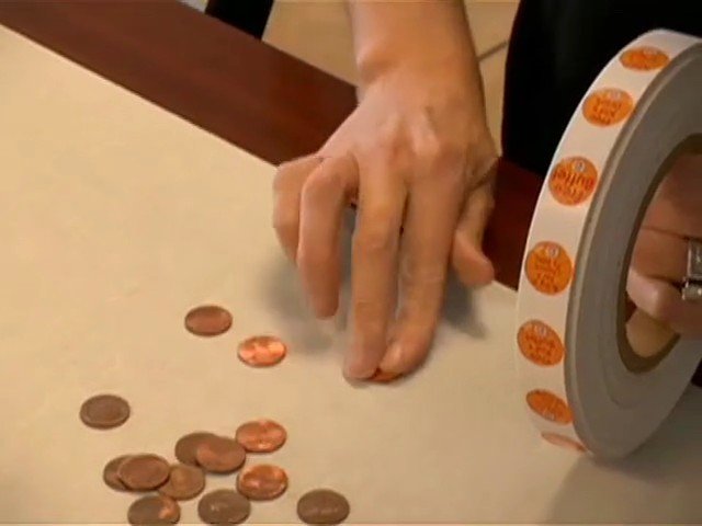 Video Reference: hand, tabletop, coins, stickers, labels, close-up, sorting, office, craft, manual work, roll, discs, desk, counting, arrangement
