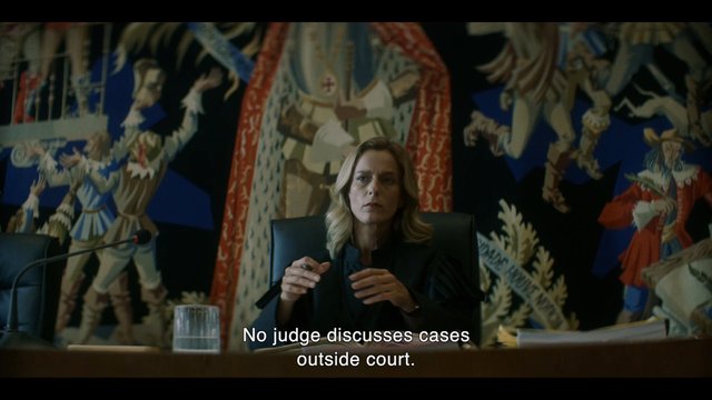 Video Reference: woman, meeting, conference room, microphone, table, mural, subtitles, courtroom, judicial, indoor, portrait, serious, office, panel, discussion, diplomatic