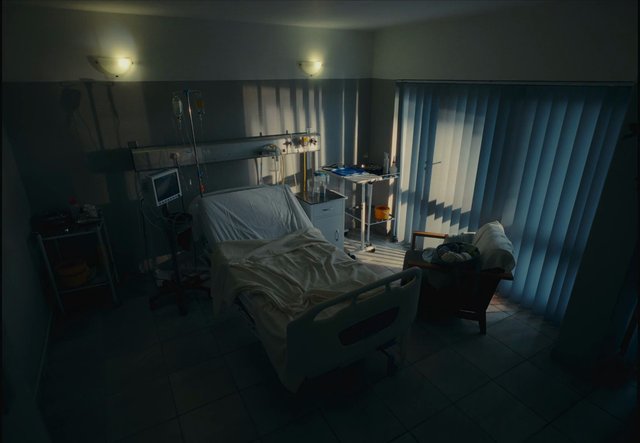 Video Reference: hospital, patient room, medical bed, IV stand, monitor, clinic, healthcare, empty room, blinds, shadows, interior, medical equipment, bedside cart, dim lighting