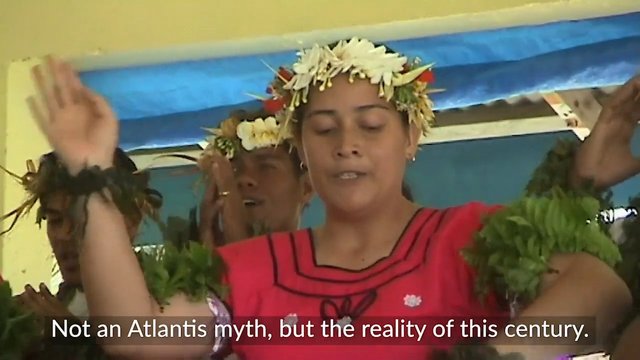 Video Reference: people, performance, dance, floral headdress, traditional costume, indoor, group, pink dress, subtitles, ceremony, festival, leaf decorations, close-up, stage, cultural event