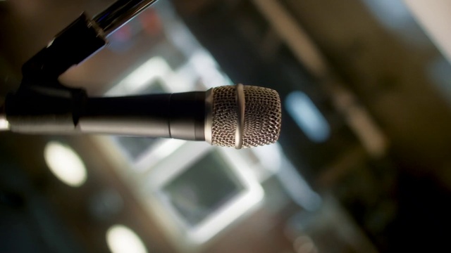Video Reference: Microphone, Audio equipment, Tints and shades, Building, Event, Microphone stand, Font, Carbon, Electric blue, Metal