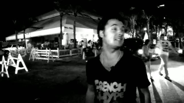 Video Reference: night, outdoor, man, street, black-and-white, building, crowd, cars, festival, urban, low-light, candid, people, walkway