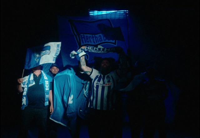 Video Reference: Sleeve, Font, Entertainment, Performing arts, Hat, Music, Electric blue, T-shirt, Event, Fashion design
