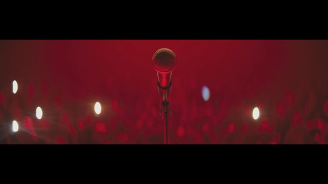 Video Reference: microphone, stage, concert, red lighting, music, performance, podium, audience, bokeh, livestream, event, empty stage
