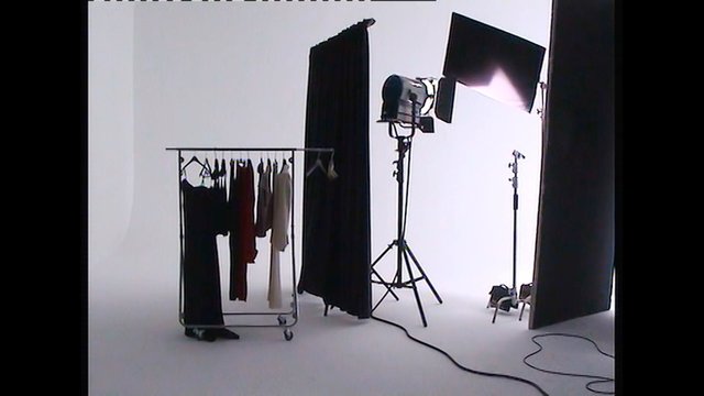 Video Reference: photo studio, lighting equipment, softbox, backdrop, clothing rack, garments, studio lights, black curtain, cables, white cyclorama, fashion shoot, tripod stand