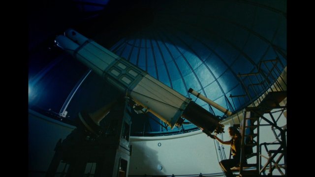 Video Reference: telescope, observatory, astronomy, dome, night, scientist, ladder, instrument, indoors, blue light, research, space, equipment, silhouette, maintenance
