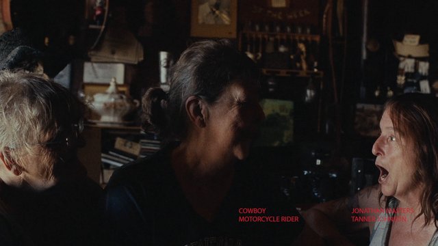 Video Reference: indoor, dimly lit, three women, close-up, conversation, surprised expression, home interior, shelves, background objects, movie credits, red text, dramatic scene
