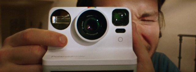 Video Reference: selfie, close-up, instant camera, camera, person, indoor, portrait, handheld, blurred background, technology, photography