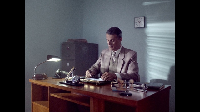 Video Reference: Table, Furniture, Desk, Blazer, Writing desk, White-collar worker, Event, Suit, Office equipment, Job