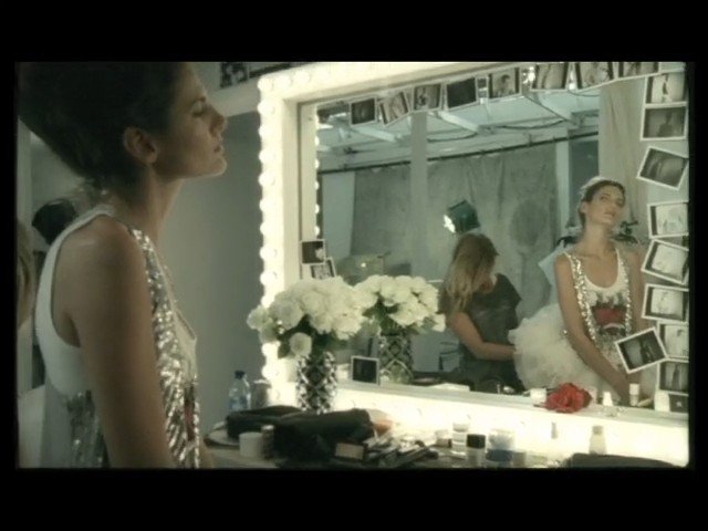 Video Reference: woman, mirror, dressing room, vanity, flowers, cosmetics, polaroids, reflection, backstage, sequined dress, indoor, portrait, makeup, fashion