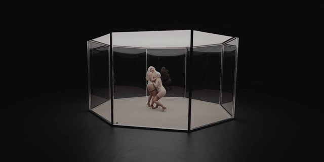 Video Reference: women, dance, studio, glass enclosure, octagonal, performance, minimalist, dark background, pose, reflection, fashion, art installation