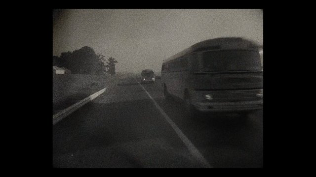 Video Reference: road, vehicles, truck, car, highway, night, low_light, grainy, black_and_white, motion_blur, traffic, outdoor, travel, transportation