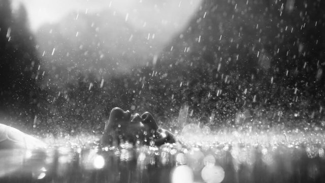 Video Reference: black and white, rain, water spray, close-up, person, dramatic lighting, bokeh, wet, outdoors, motion blur, cinematic, abstract, reflection, weather