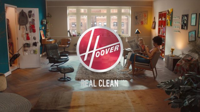 Video Reference: living room, interior, people, chairs, window, rug, plants, wall art, home decor, advertisement, logo, text overlay, modern, sunlit, residential