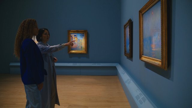 Video Reference: art museum, gallery, paintings, women, indoor, exhibition, blue walls, framed art, viewing art, tourism, culture, portrait orientation, museum interior, curation